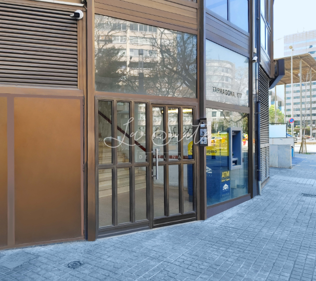 Porte principale en aluminium et verre de la façade de la maison close La Suite Barcelona visible depuis la rue Tarragona 177. | Las Suite BCN